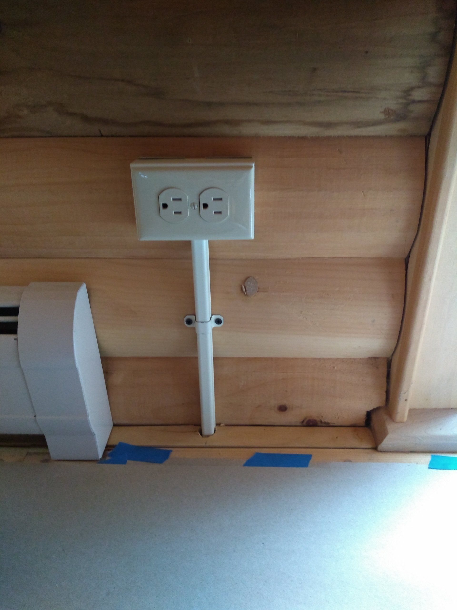 a white electrical outlet attached to a wooden wall.
