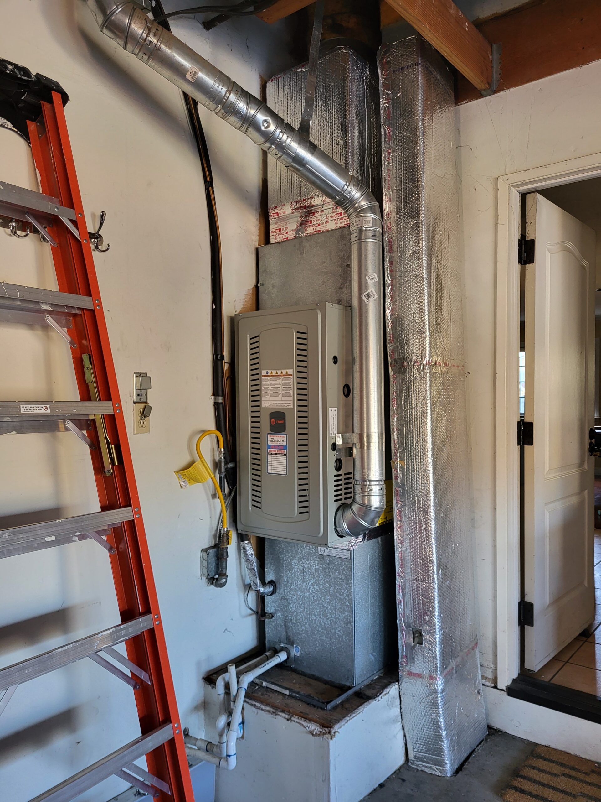 A ladder is sitting next to a heater in a room.