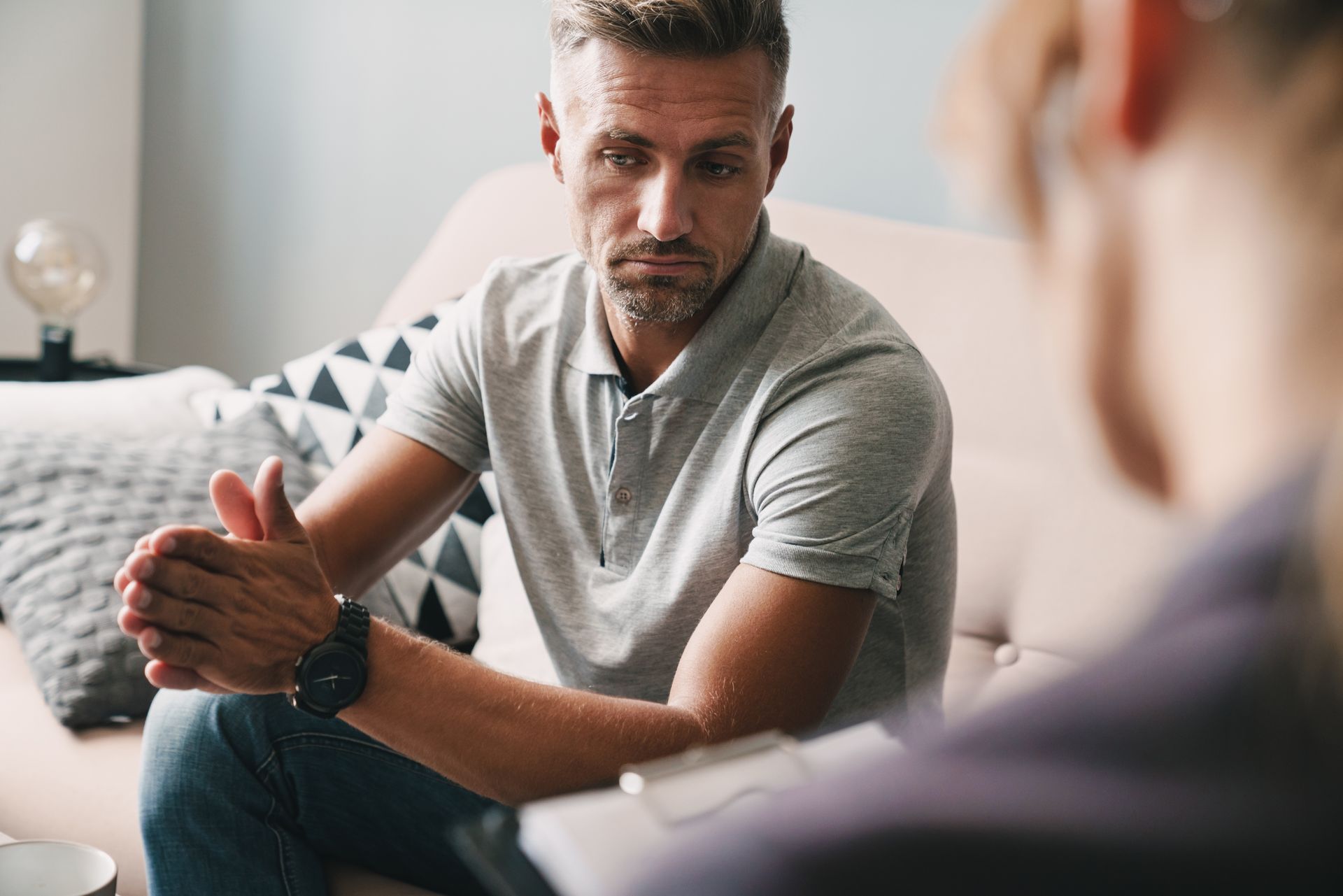 A man is sitting on a couch talking to a woman.