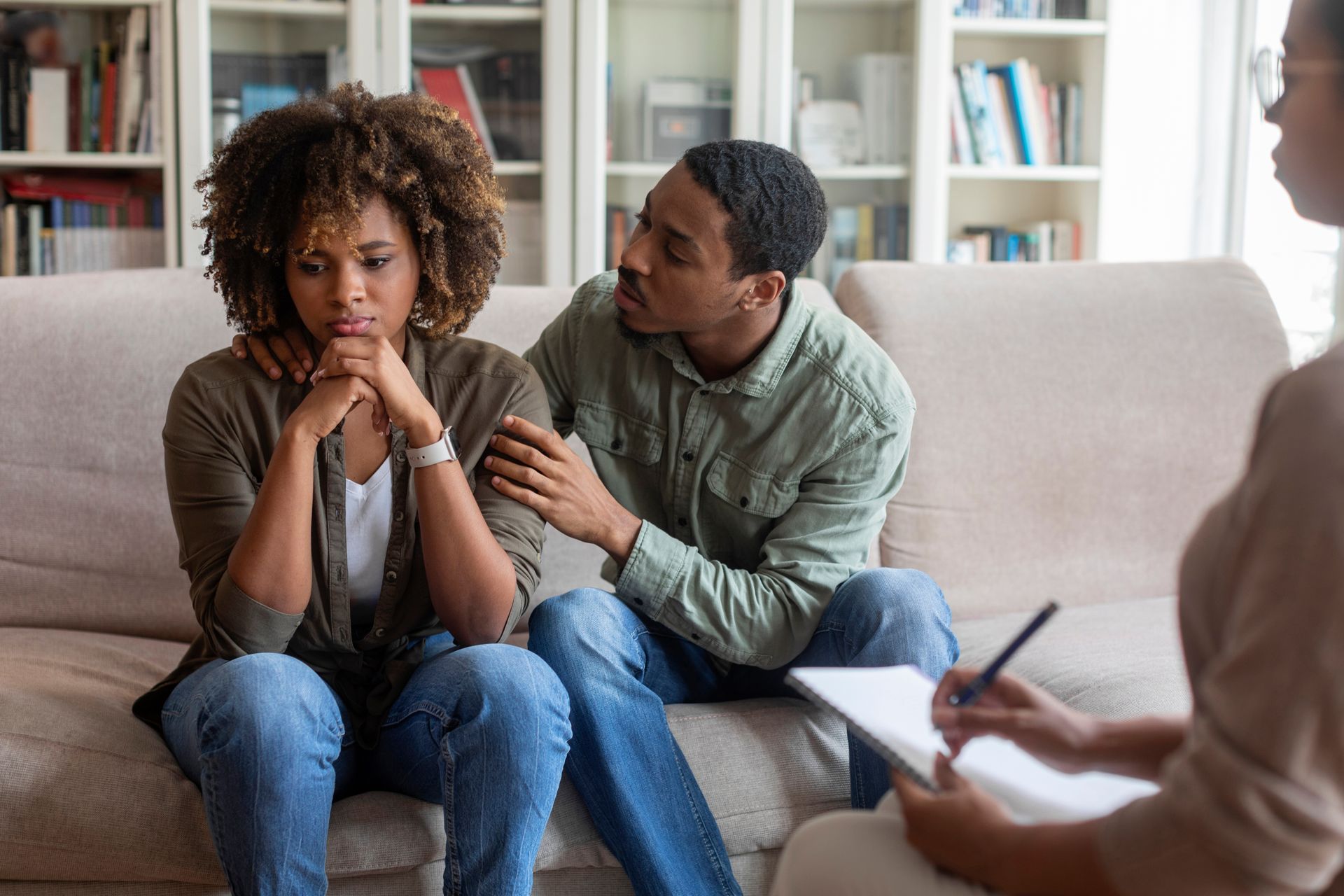 A man and a woman are sitting on a couch talking to a therapist.