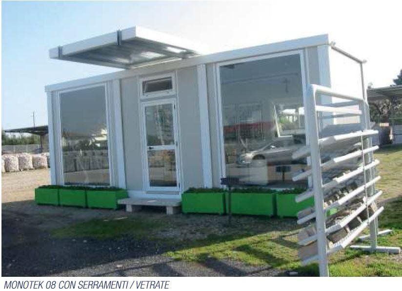 Un piccolo edificio bianco con fioriere verdi davanti