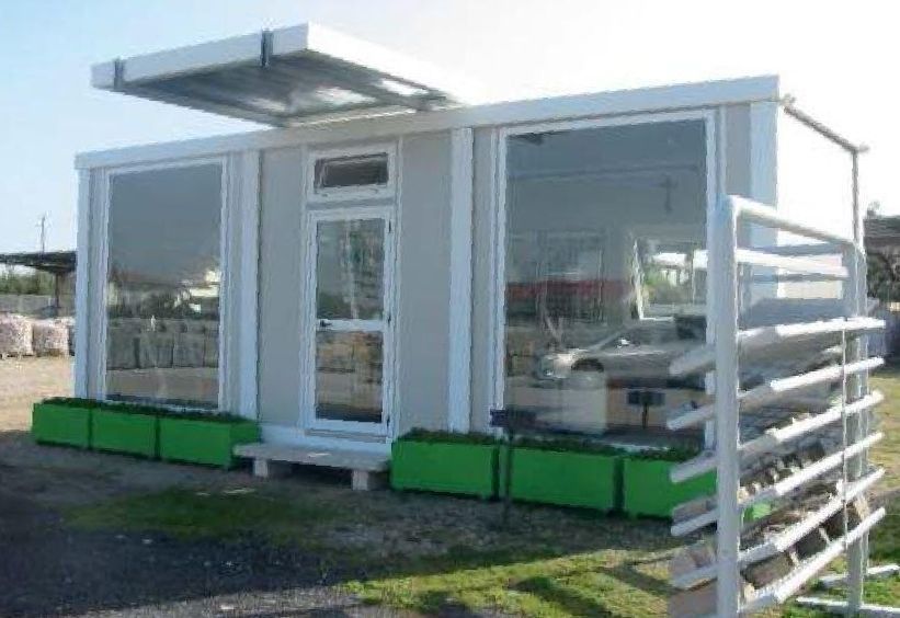 Un piccolo edificio bianco con fioriere verdi davanti