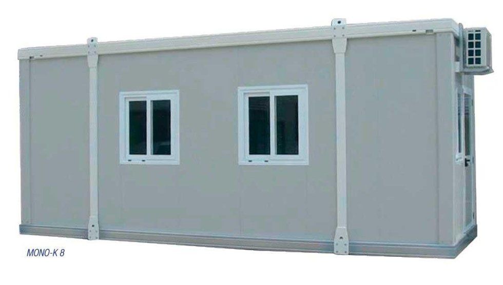 Un lungo edificio grigio con due finestre e un condizionatore