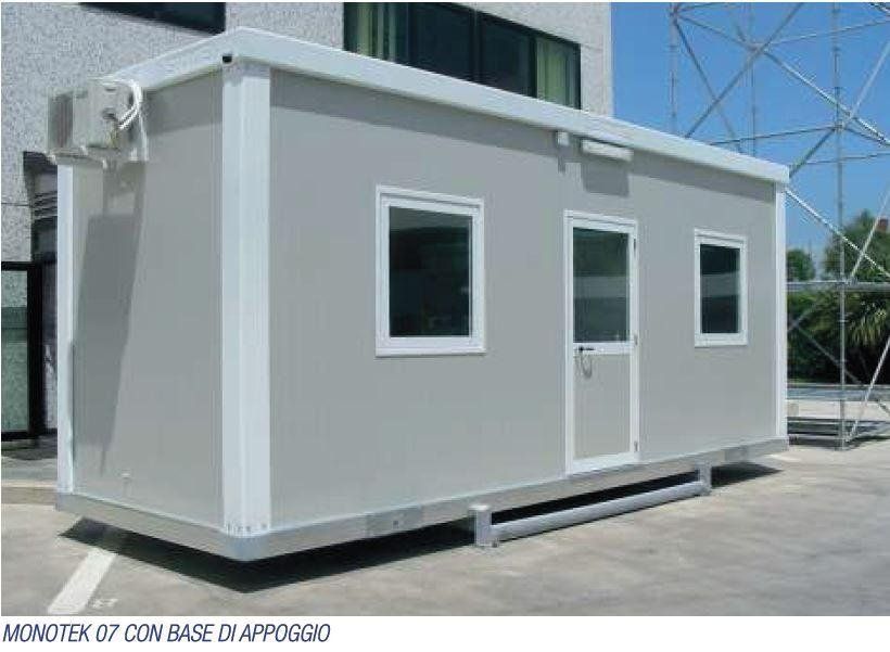 Davanti ad un edificio è parcheggiato un edificio trasportabile con porta e finestre.