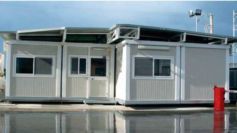 Un edificio bianco con davanti un bidone della spazzatura rosso