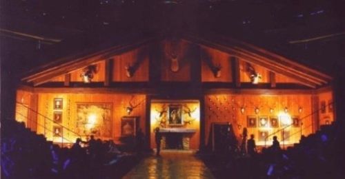 Un gruppo di persone è raccolto all'interno di un grande edificio in legno