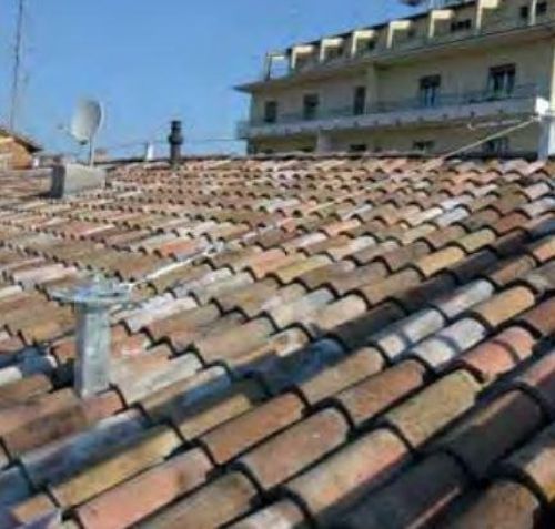 Un tetto con molte tegole e un edificio sullo sfondo.