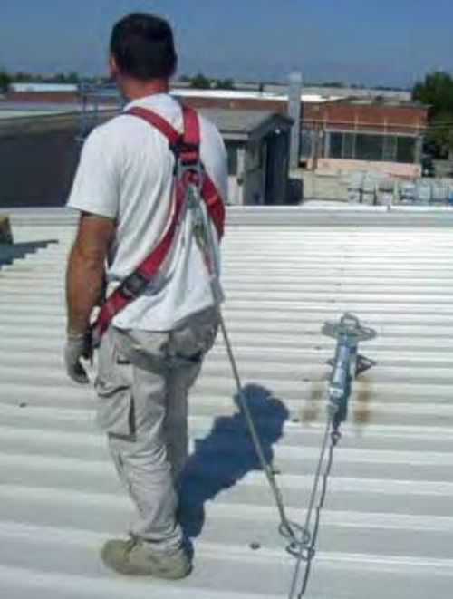 Un uomo che indossa un'imbracatura di sicurezza è in piedi su un tetto