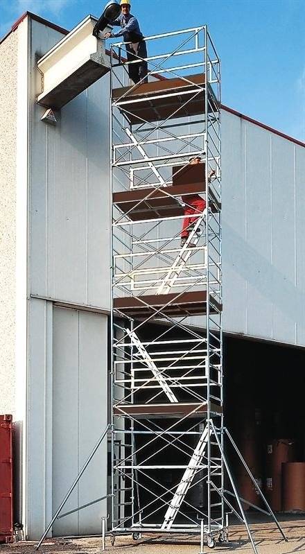 Un uomo è in piedi in cima a un'impalcatura di fronte a un edificio.