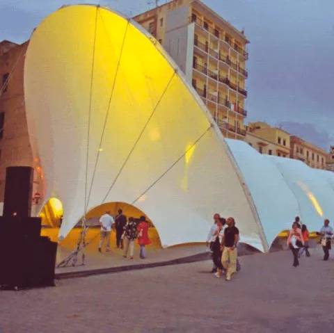 Un gruppo di persone in piedi davanti a una grande tenda bianca