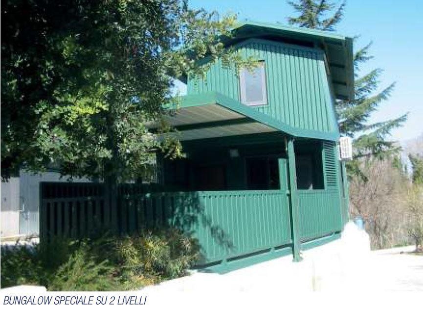 Una casa verde con balcone e un cartello che dice bungalow speciale su 2 livelli