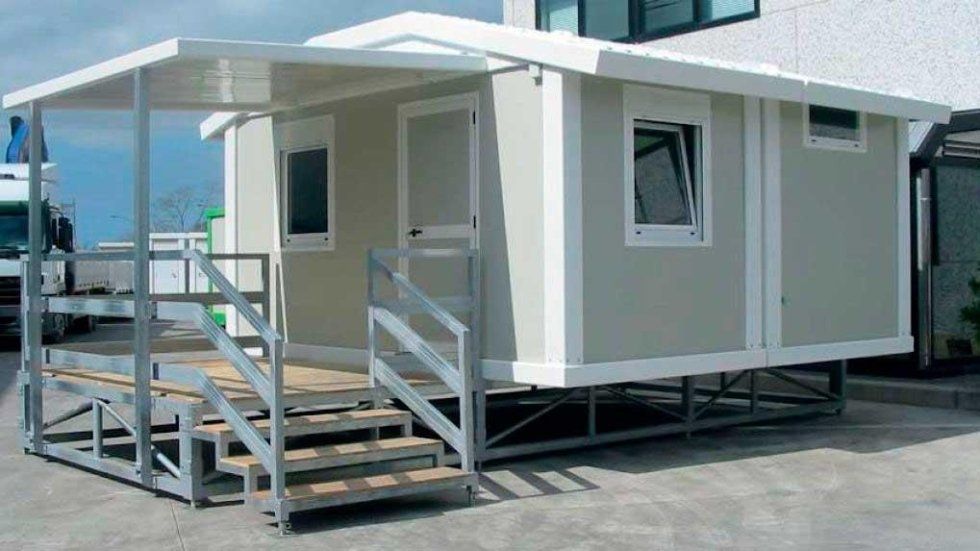 Una piccola casa con scale che vi conducono si trova in un parcheggio.