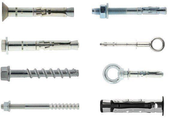 Ci sono molti tipi diversi di viti e bulloni su uno sfondo bianco.