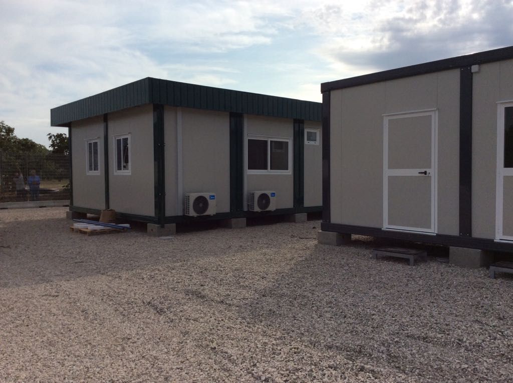 Un gruppo di edifici mobili sono posti uno accanto all'altro in un terreno di ghiaia.