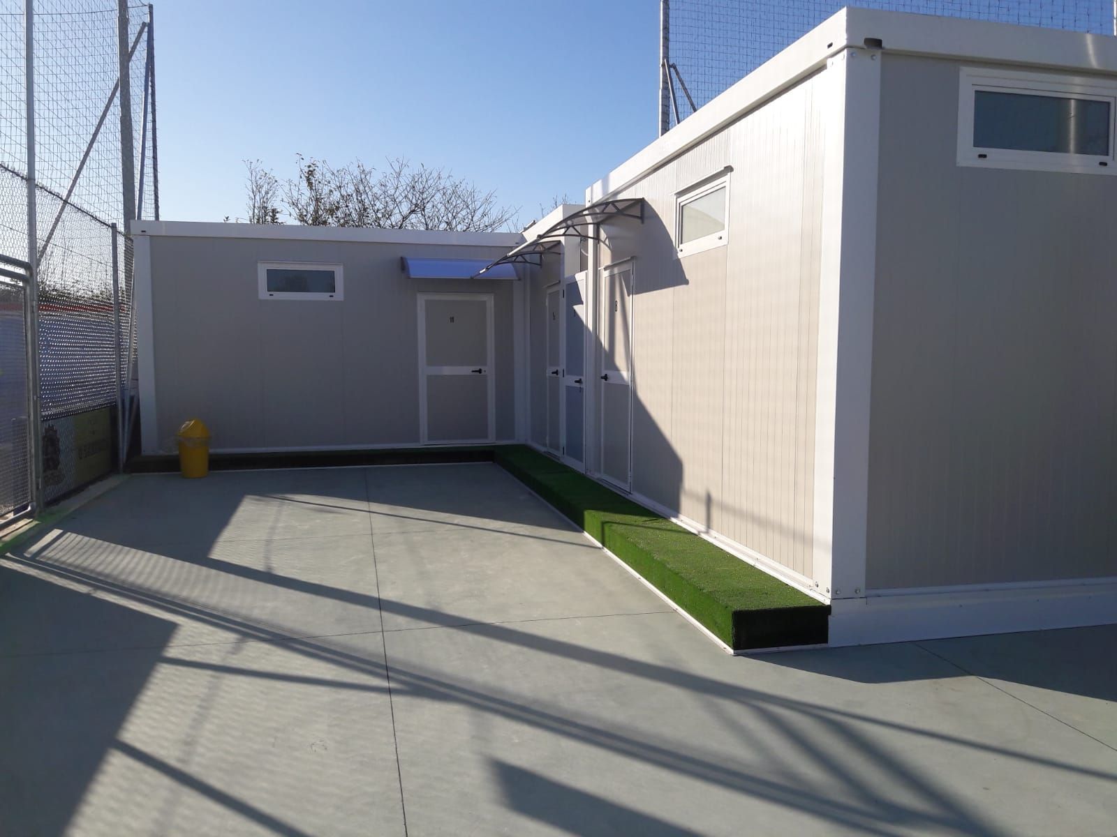 Un edificio grigio e bianco con una recinzione sullo sfondo