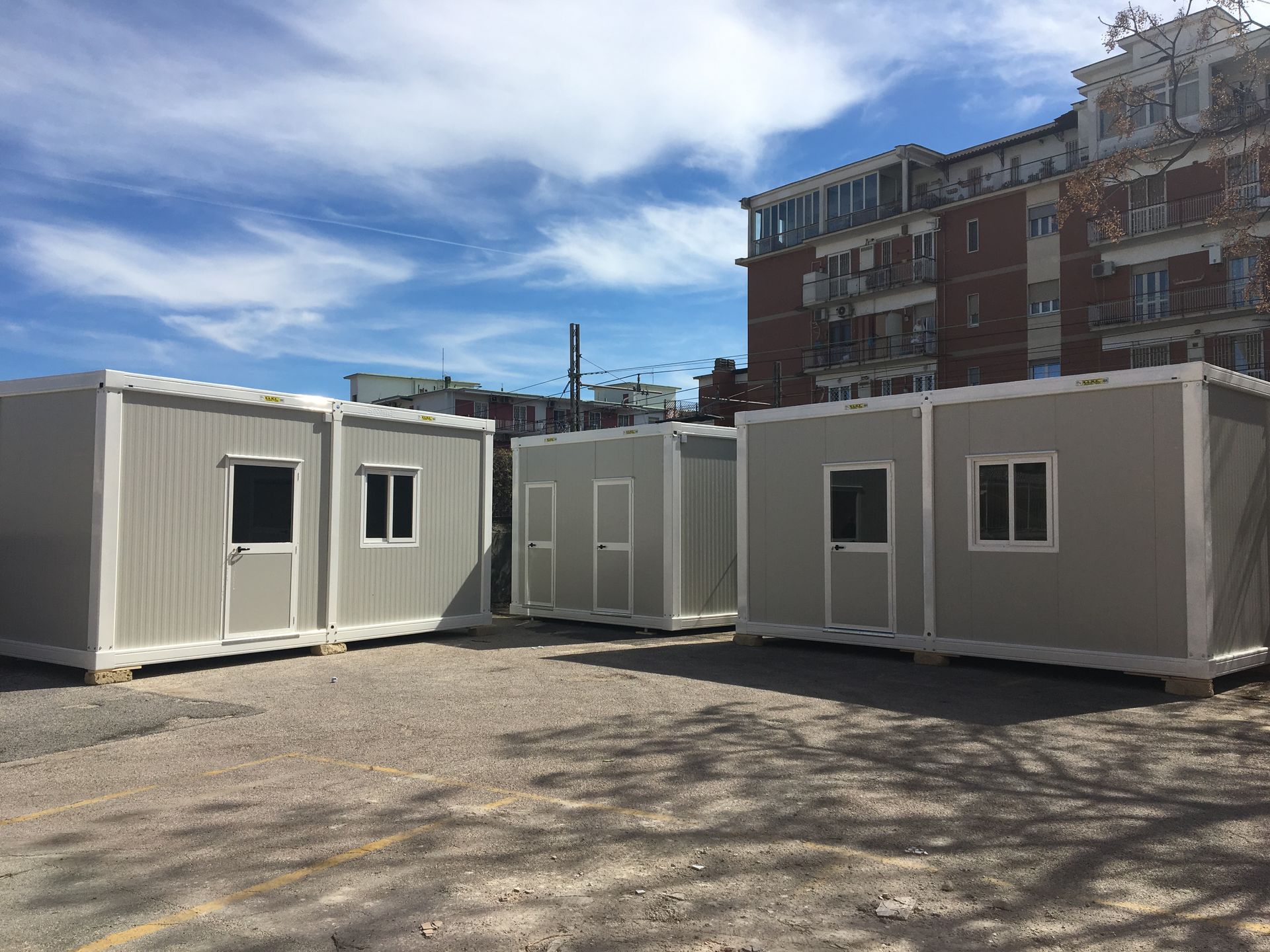 Un gruppo di container si trova nel parcheggio di fronte a un edificio.