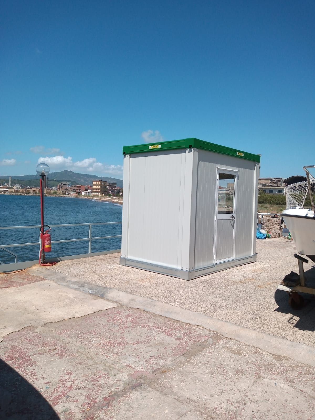 Un piccolo edificio bianco con un tetto verde si trova accanto a uno specchio d'acqua.