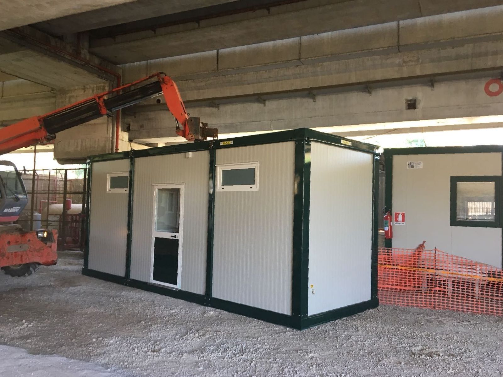 Una gru sta sollevando un container in un edificio.