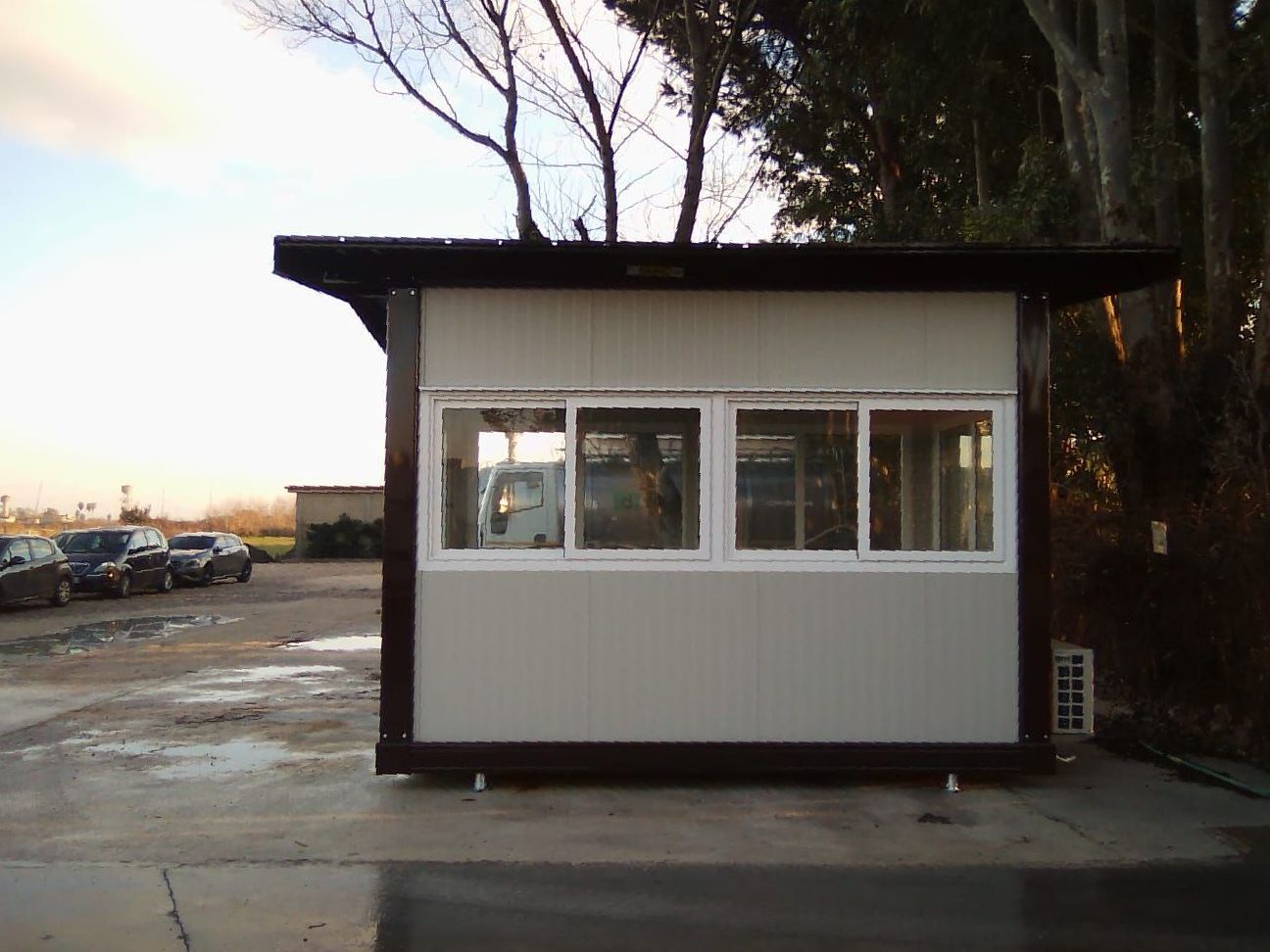 Un piccolo edificio con molte finestre in un parcheggio