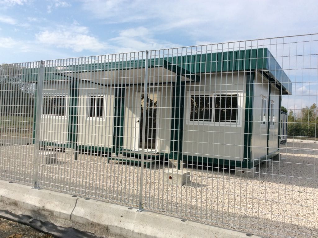 Dietro una recinzione si trova un edificio con tetto verde.