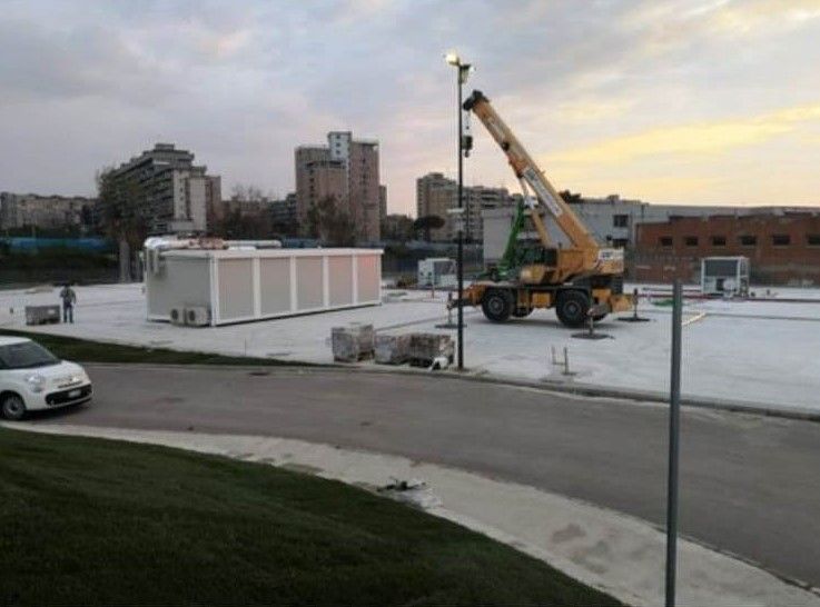 Una gru gialla è ferma in un parcheggio accanto a un furgone bianco.