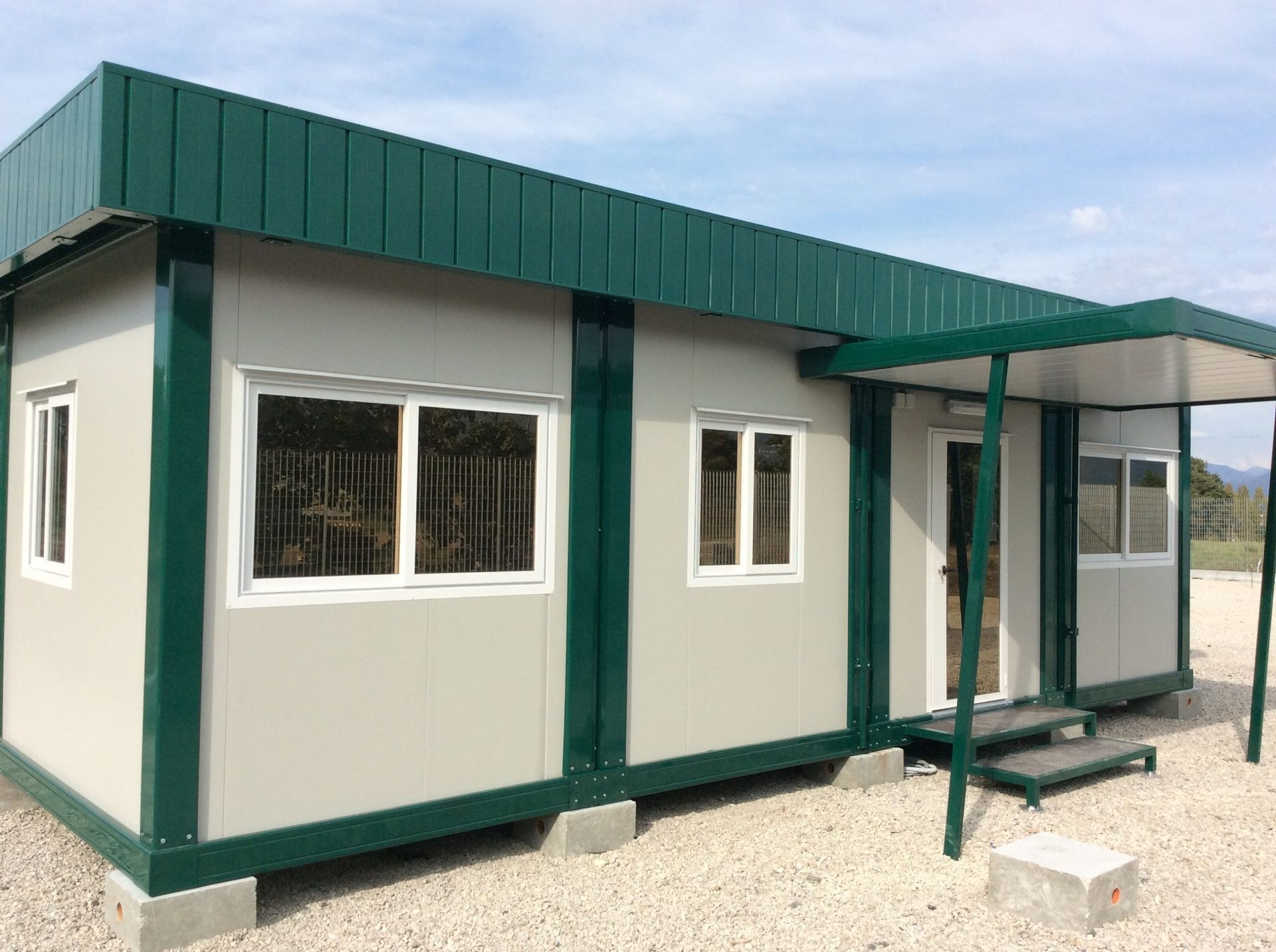 Una piccola casa bianca con tetto verde e scale.