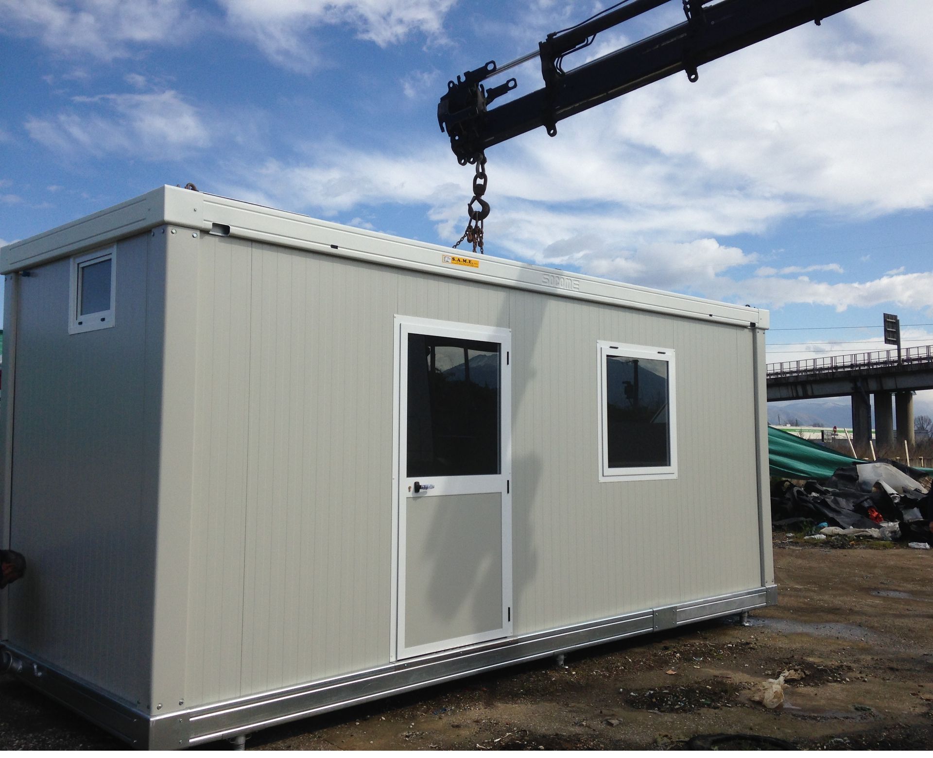 Un piccolo edificio bianco viene sollevato da una gru