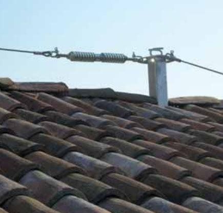 Un primo piano di un tetto di tegole con una linea elettrica collegata ad esso.