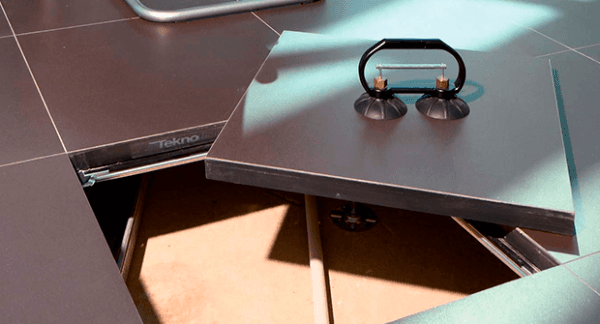 Su un pavimento piastrellato è posato un tavolino con maniglia.