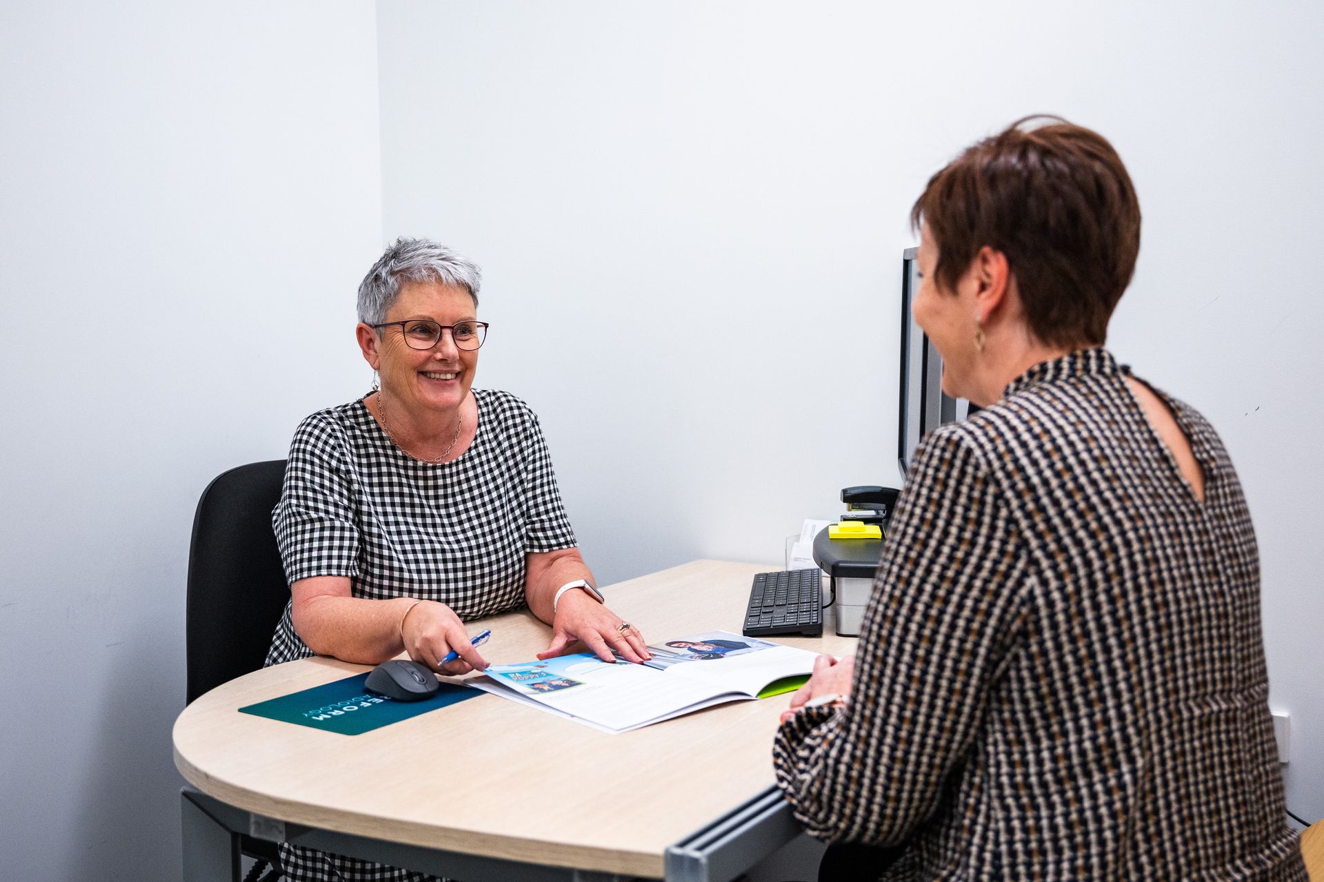 Two women are sitting at a table talking to each other