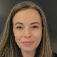 A portrait of a person with shoulder-length, light-brown hair, smiling softly against a dark gray background.