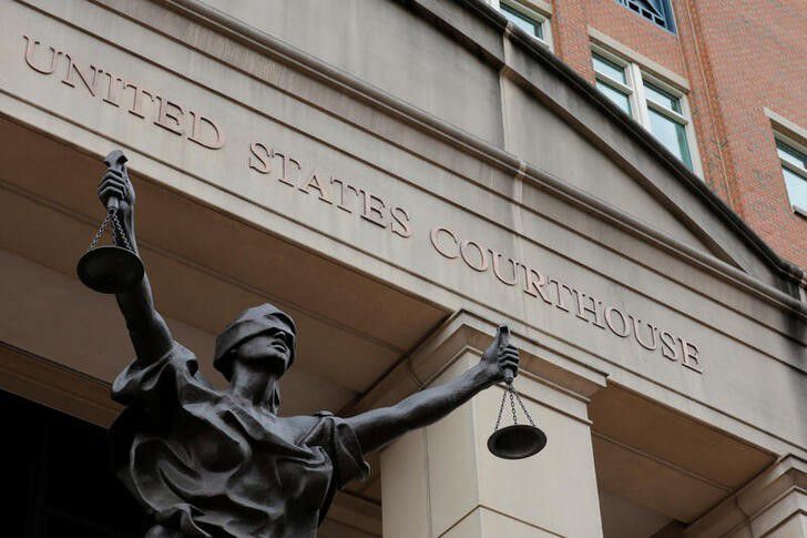 A statue of Lady Justice in front of a United States Courthouse building.