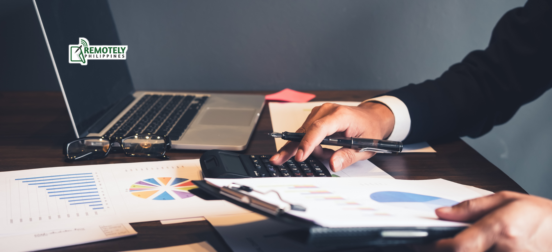 Person using a calculator, laptop, and financial documents on a desk.