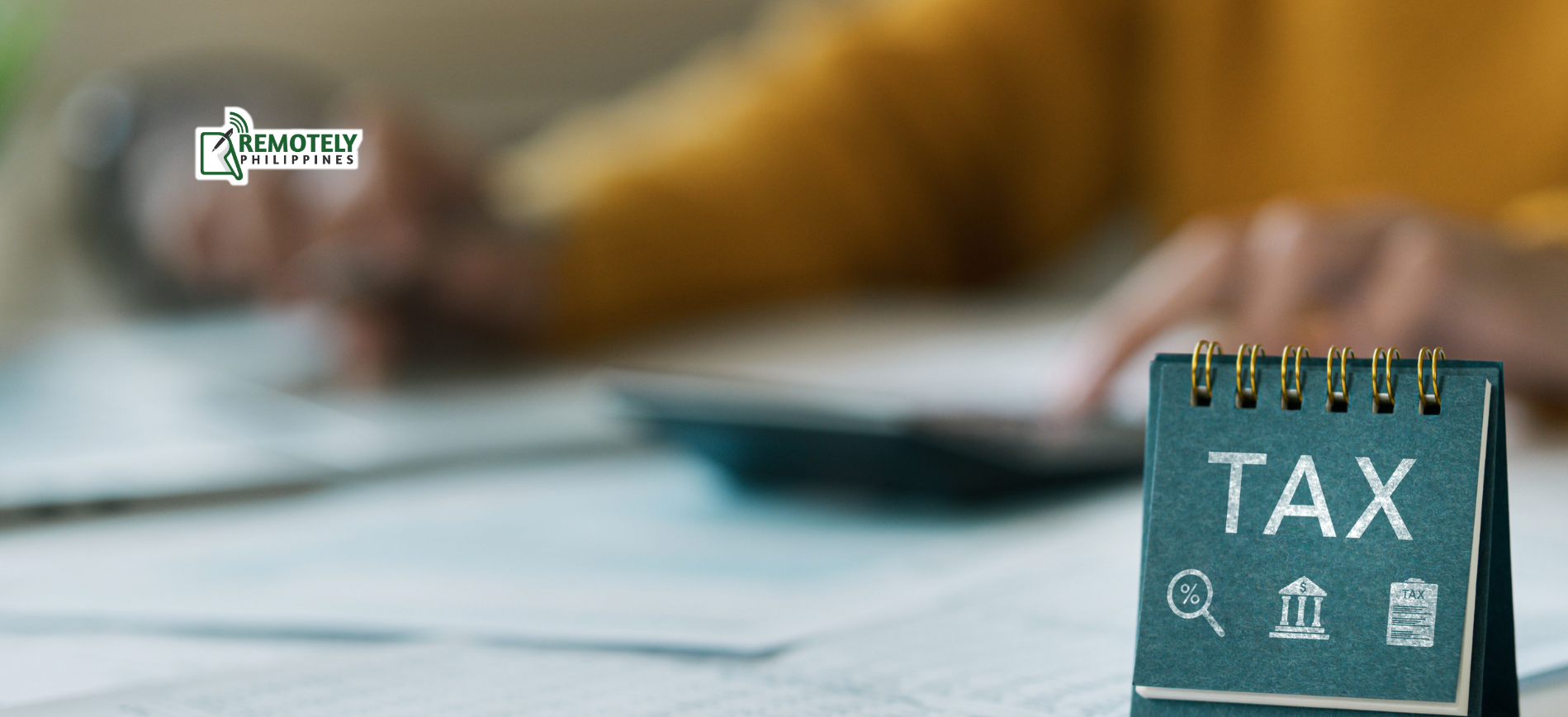 Desk with tax notepad and calculator, with a person working in the blurred background