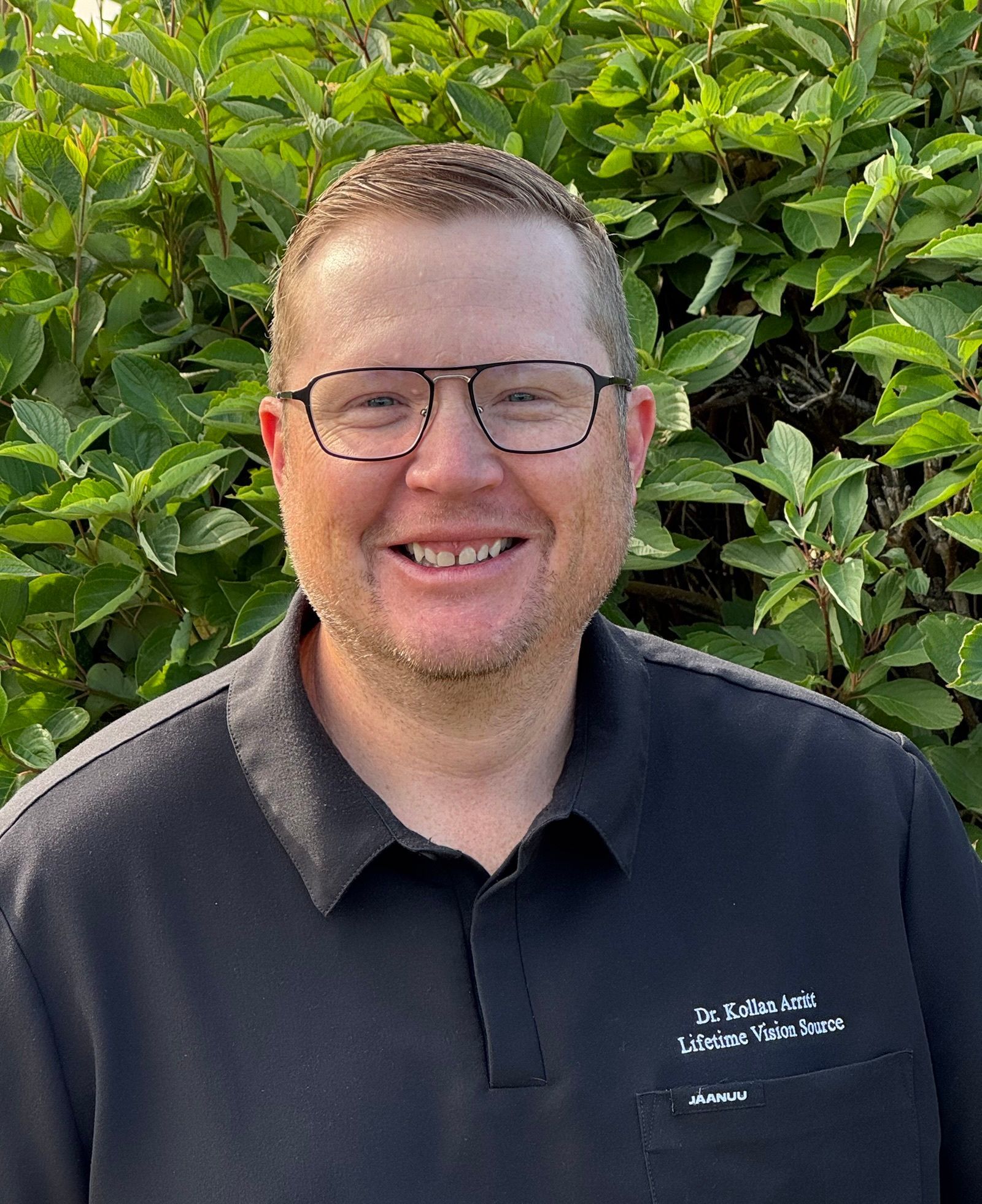 A woman wearing glasses and a blue sweater is smiling for the camera.