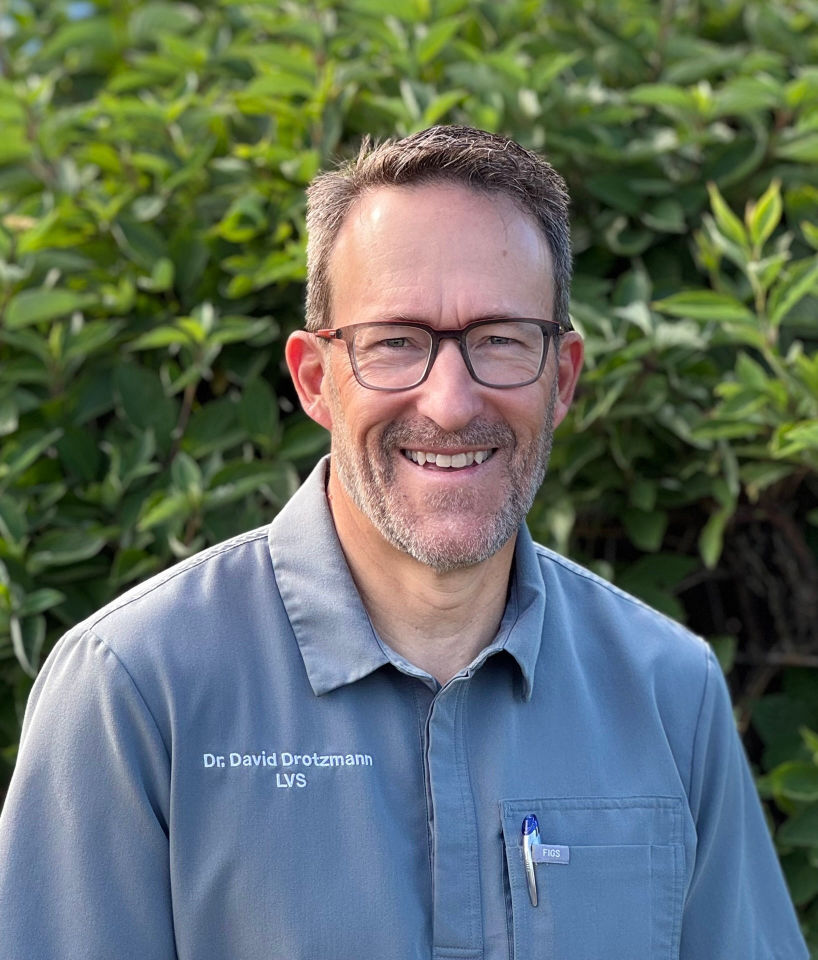 A woman wearing glasses and a blue sweater is smiling for the camera.