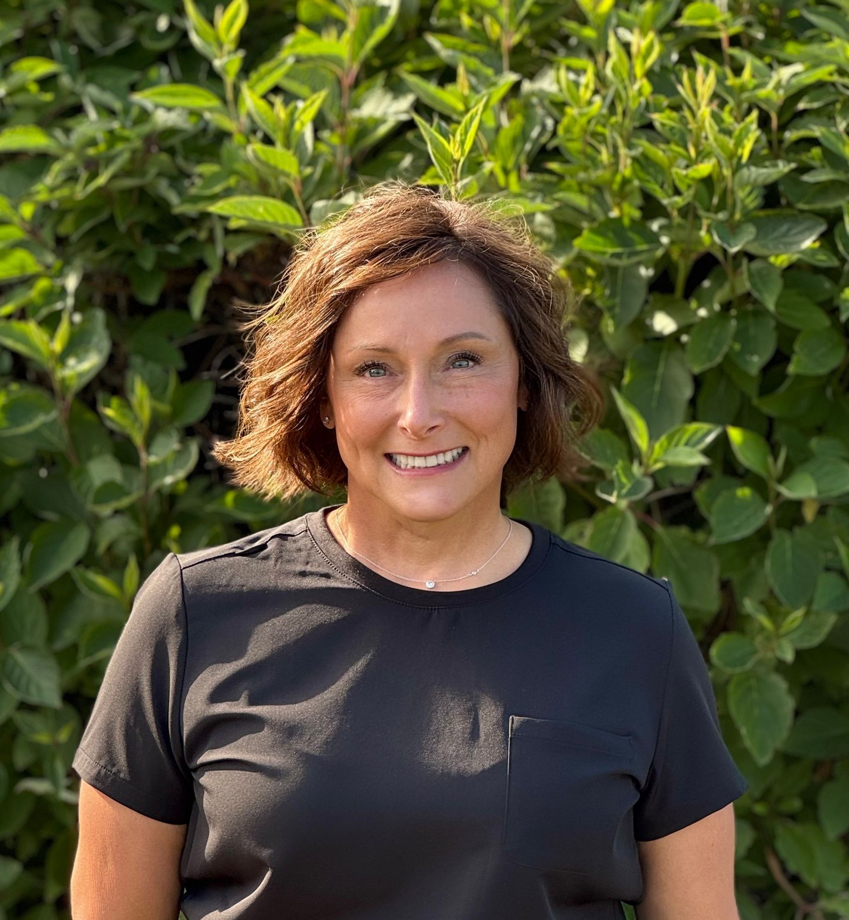 A woman wearing glasses and a blue sweater is smiling for the camera.