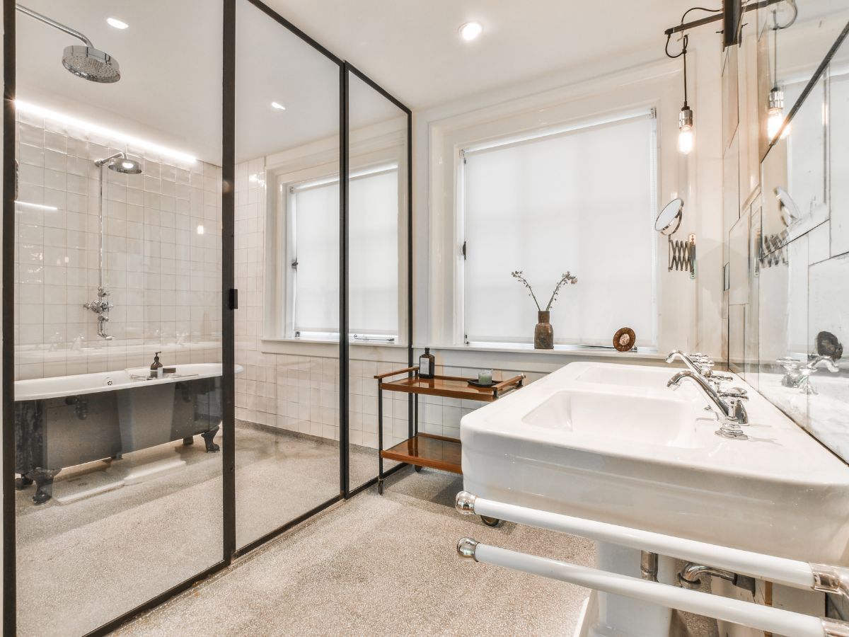 Modern bathroom with glass shower, white vanity, large mirror, and freestanding tub