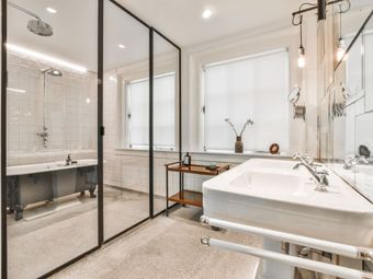 Modern bathroom with glass shower, white vanity, large mirror, and freestanding tub