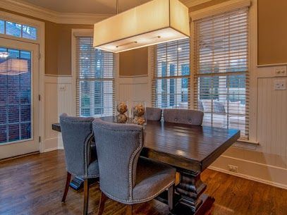 Dining room with a wooden table, blue chairs, and large windows with blinds.