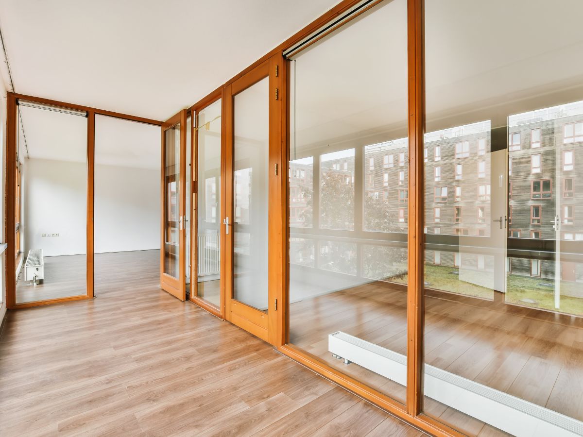 Empty modern room with wood floors and glass doors overlooking a balcony