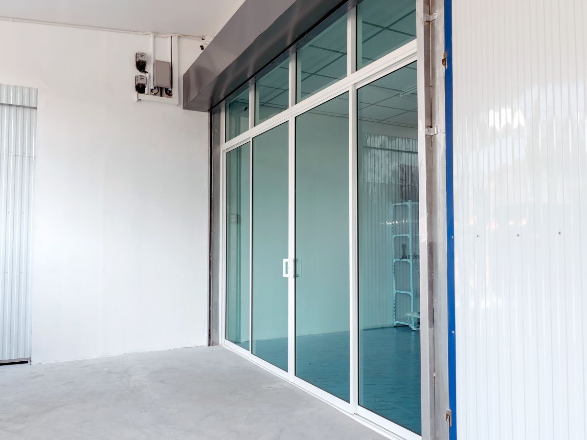 Empty corridor with white walls and blue-tinted glass sliding doors