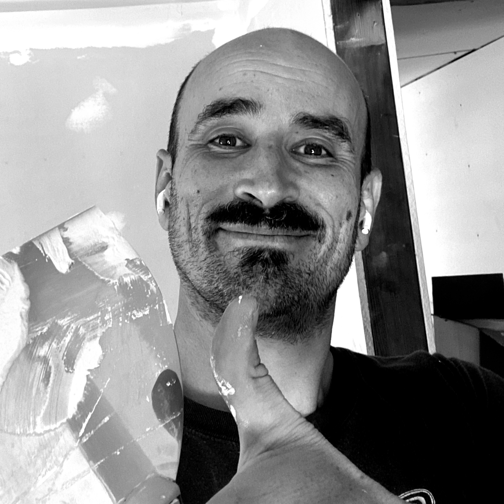 Justin Gibbs in black and white and holding drywall tools and giving a thumbs up