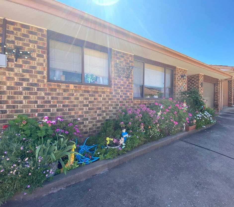 A brick house with flowers and a hose in front of it