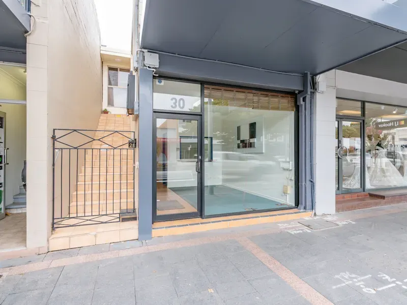 A store front with a large glass door and a fence.