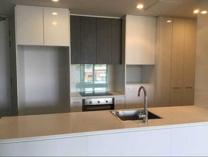 An empty kitchen with white cabinets and a sink