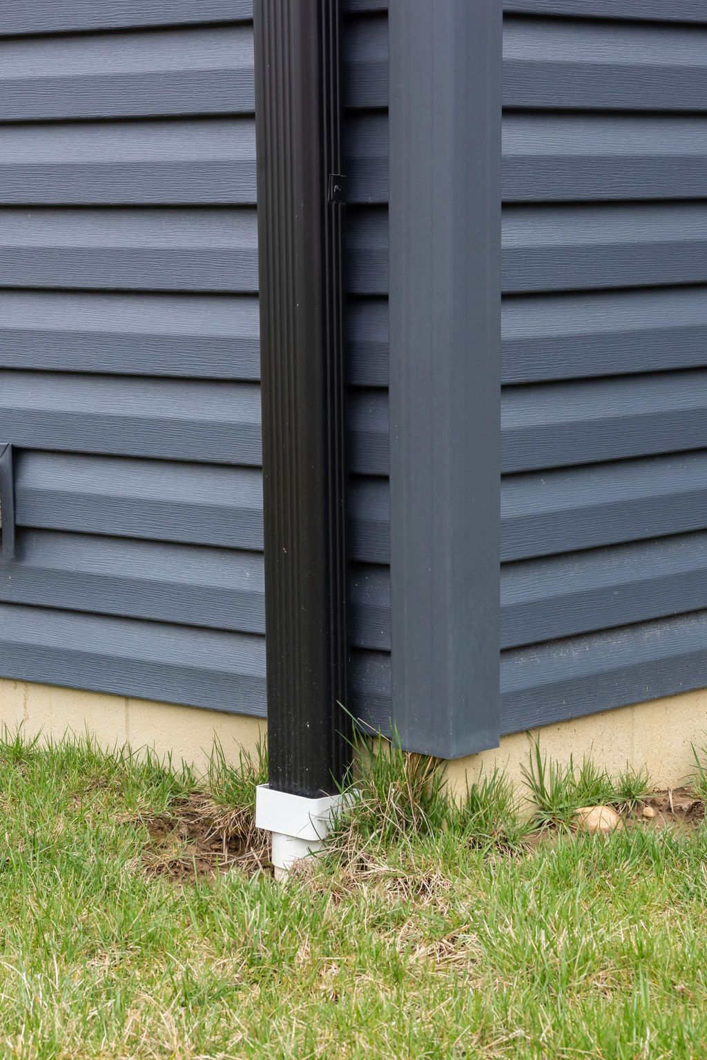 A black gutter is on the side of a house.