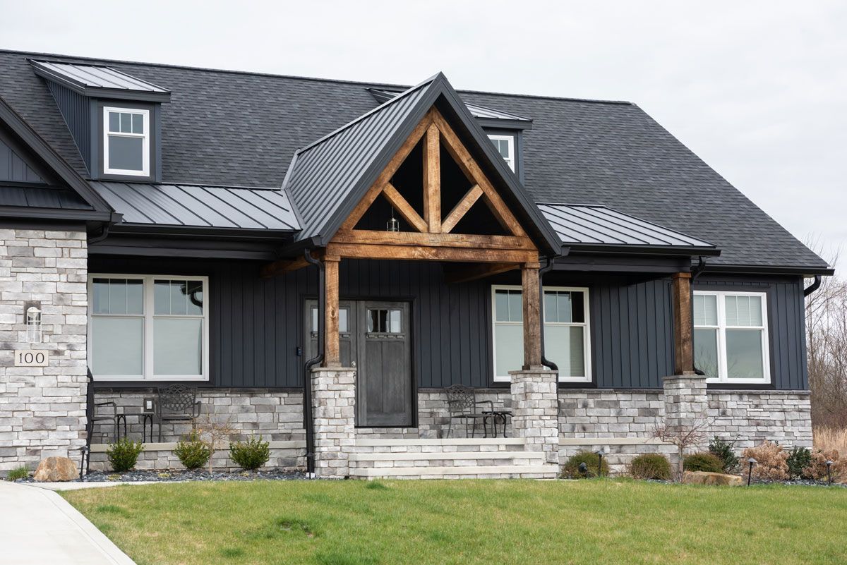 A large house with a black roof and a wooden porch.