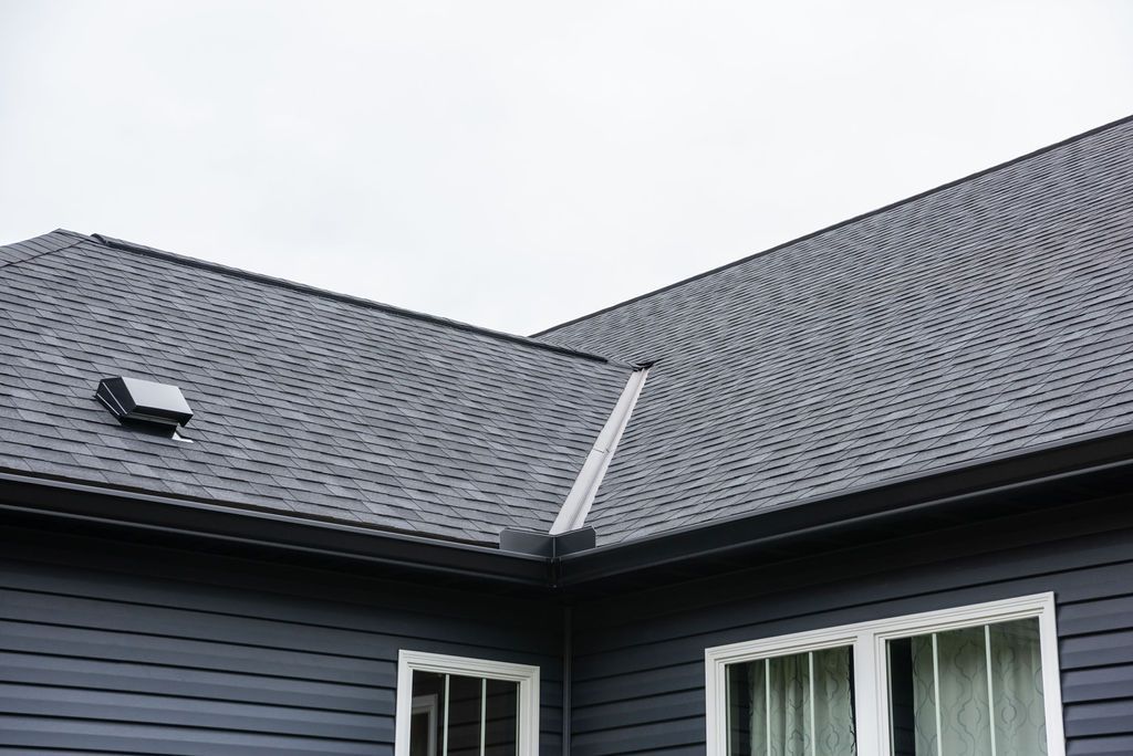 A black house with a gray roof and white windows.