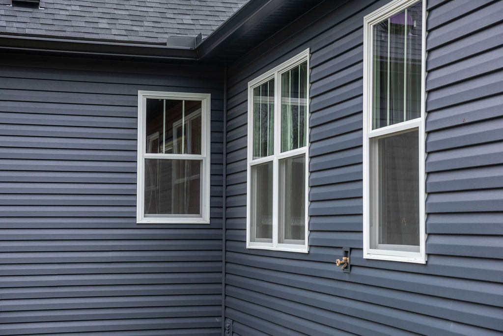 The side of a house with blue siding and white windows.